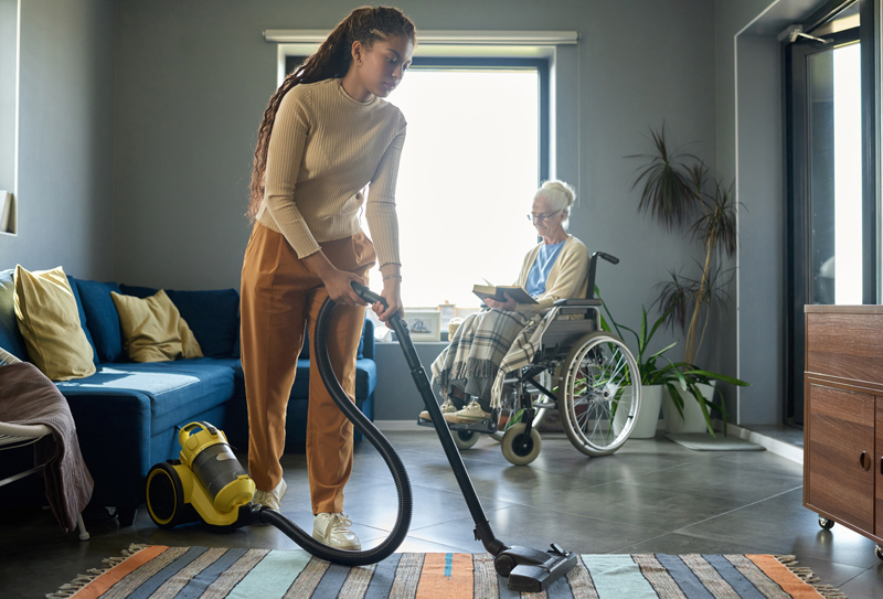 Cute teenage girl in casualwear cleaning floor with vacuum cleaner